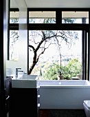 Zeitgenössisches Bad im Schwarzweiss mit Blick durch geöffnete Glasschiebetür auf die Landschaft