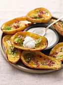 Baked potato skins topped with bacon, spring onions and sour cream
