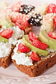 Rye bread with cottage cheese, strawberries and avocado; fruit and coconut skewers in the background