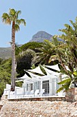 Terrace with white awnings adjoining house with stone walls in South African landscape
