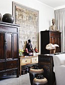 Hodgepodge of Chinese furniture and objets d'art from around the world in white interior with large, Chinese painting on wall