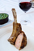 Lamb Chop on a White Plate; Glass of Red Wine