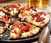 Pizza mit Paprika und Schinken, in Stücke geschnitten