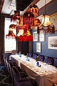 Gedeckte Esstafel unter nostalgischem Lampenhimmel; die Stühle mit gesteppter Rückenlehne harmonieren mit der blauen Wandfarbe