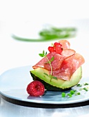 A wedge of avocado with salami and berries