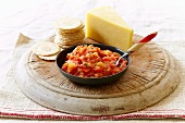 Spicy tomato relish with crackers and cheese on a wooden board