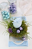An egg decorated with a ribbon and chocolate eggs in an Easter nest made of moss and grass