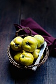 Several quinces in a basket with a knife