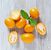 Kumquats on a wooden slab with mint, viewed from above