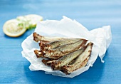 A pile of sprats on crumpled white paper on a blue surface