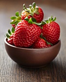 Fresh strawberries in brown ceramic bowl