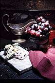 Blauschimmelkäse auf Käsebrett, Schale mit roten Trauben und antike Sauciere