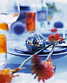 Disco ball, sprigs of flowers & decorative fish on place setting
