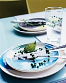 Rispe und Blumenknospe auf Gedeck und in Wasserglas auf Tisch