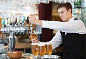 A waiter pouring draught beer in a pub
