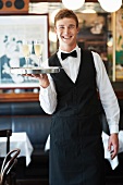 A waiter holding a tray with two glasses of sparkling wine in a restaurant