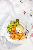 Breaded prawns on small skewers with a dip and salad