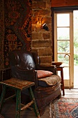 Old leather armchair in corner of room next to French windows in simple country house