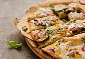 Mushroom, Red Onion, Yellow Pepper and Basil Pizza; Sliced on Pizza Board