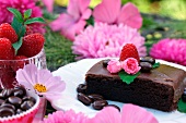 Schokoladenkuchen auf Dessertteller inmitten pinkfarbener Blütendekoration