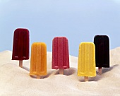 Five Assorted Fruit Popsicles; Standing in Sand