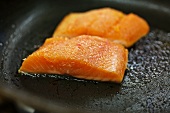 Salmon trout being fried in a pan