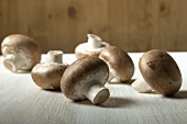 Several fresh chestnut mushrooms on a wooden table
