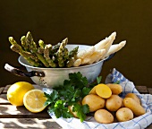 Spargel im Sieb, Zitronen, Petersilie und Kartoffeln