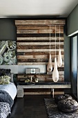 Teardrop-shaped pendant lamps in front of upcycled wood wall element in bedroom