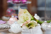 Christmas table centrepiece of white amaryllis and baubles on set table