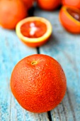 A blood orange with blood orange halves in the background