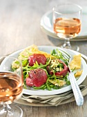 Rolled carpaccio of beef with artichoke on a bed of salad with parmesan crisps