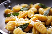 Gnocchi with sage and parmesan in a frying pan (close-up)