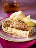 A pancake with sardine mousse and lime wedges