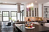 Freistehender Küchenblock unter modernen Hängeleuchten mit farbigen Glasschirmen