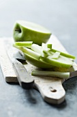 A partly sliced Granny Smith apple on a chopping board