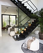Black, lacquer zig zag stairs in an open living room with upholstered furniture in bright, gray fabric