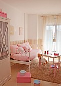 Romantisches Kinderzimmer in zartem Rosa mit Metallbett als Tagessofa und Teddybär an Kindertisch