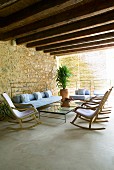 Mediterranean terrace with casual cushioned seating, row of comfortable rocking chairs and modern steel and glass tables