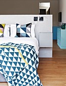 Bed linen with geometric patterns on double bed against partition headboard