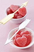 Heart-shaped bonbons in bowls with Cupid's arrows