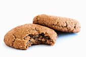 Two Oatmeal Cookies; One Bitten; On a White Background