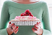 A Woman Holding a Pavlova Topped with Raspberries