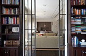 Open sliding glass doors flanked by bookcases and view of pale sofa set in modern living room