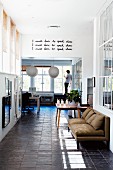 Lobby with sofa across from a picture wall; man leaning on a window in a living room