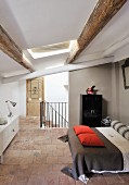 Offener Schlafbereich mit Doppelbett in renoviertem Dachgeschoss mit Holzbalkendecke in rustikalem Ambiente