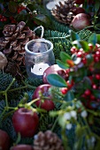 Christmas arrangement of fir branches, wintergreen, bay, apples, mistletoe, pine cones and tealight holder