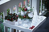 Christmas decorations on terrace: arrangement on cake stand, tealight holders, potted Gaultheria