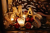 Christmas arrangement with the letters XMAS, tealight holders, fairy lights and red apples
