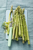 Green asparagus with a peeler on a chopping board